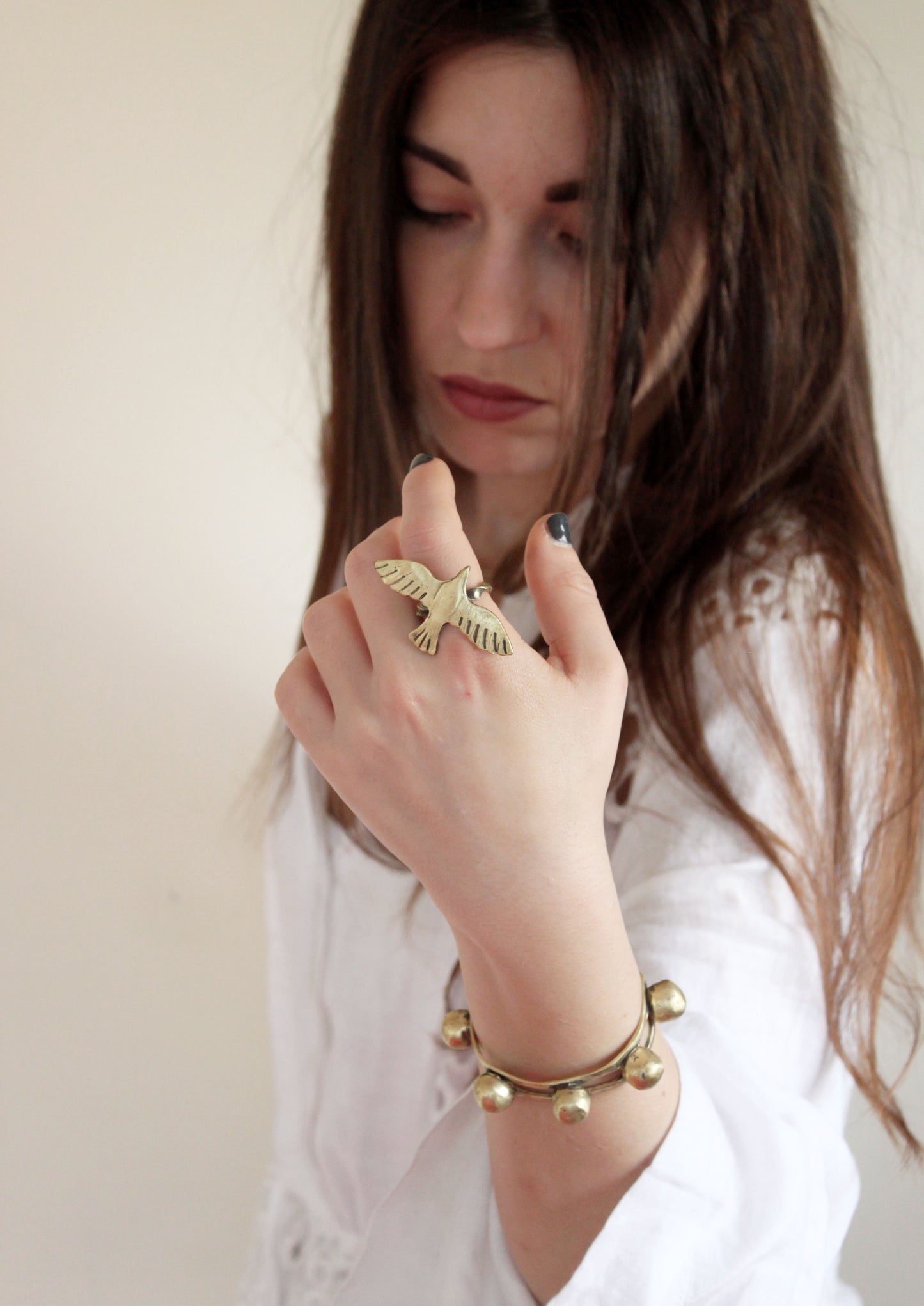 Woman wearing gold jewelry including a gold bird ring and bracelet