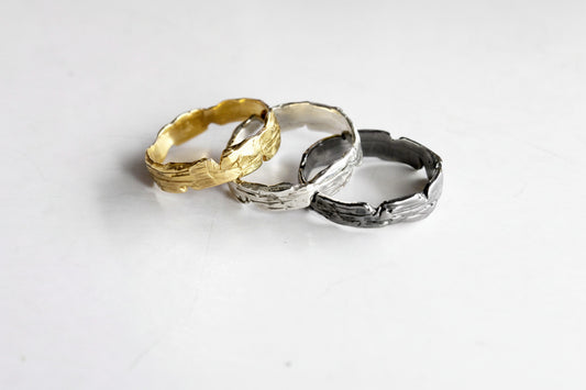 Three rings in gold, silver, and black