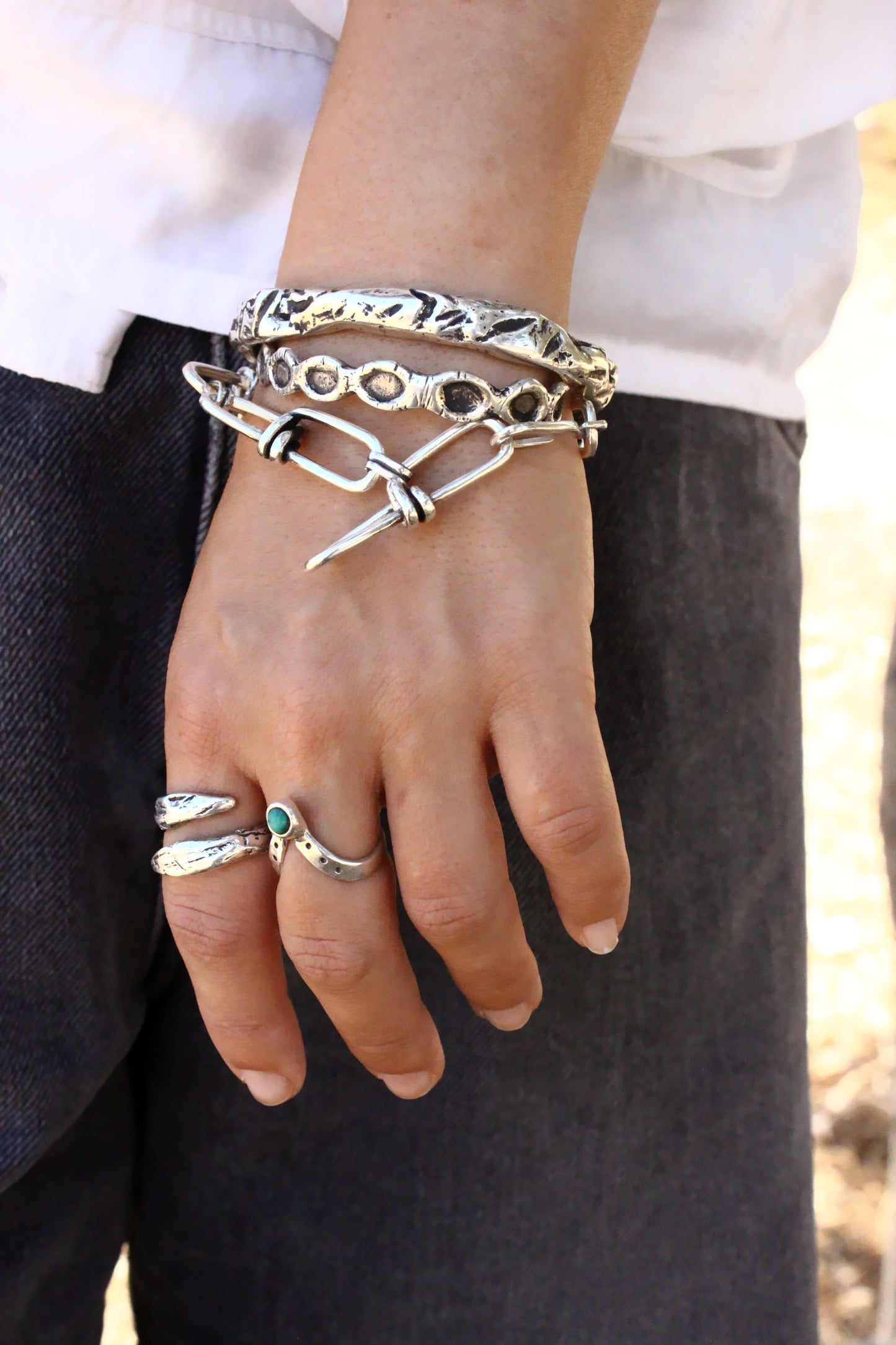 Hand wearing multiple bracelets and rings 