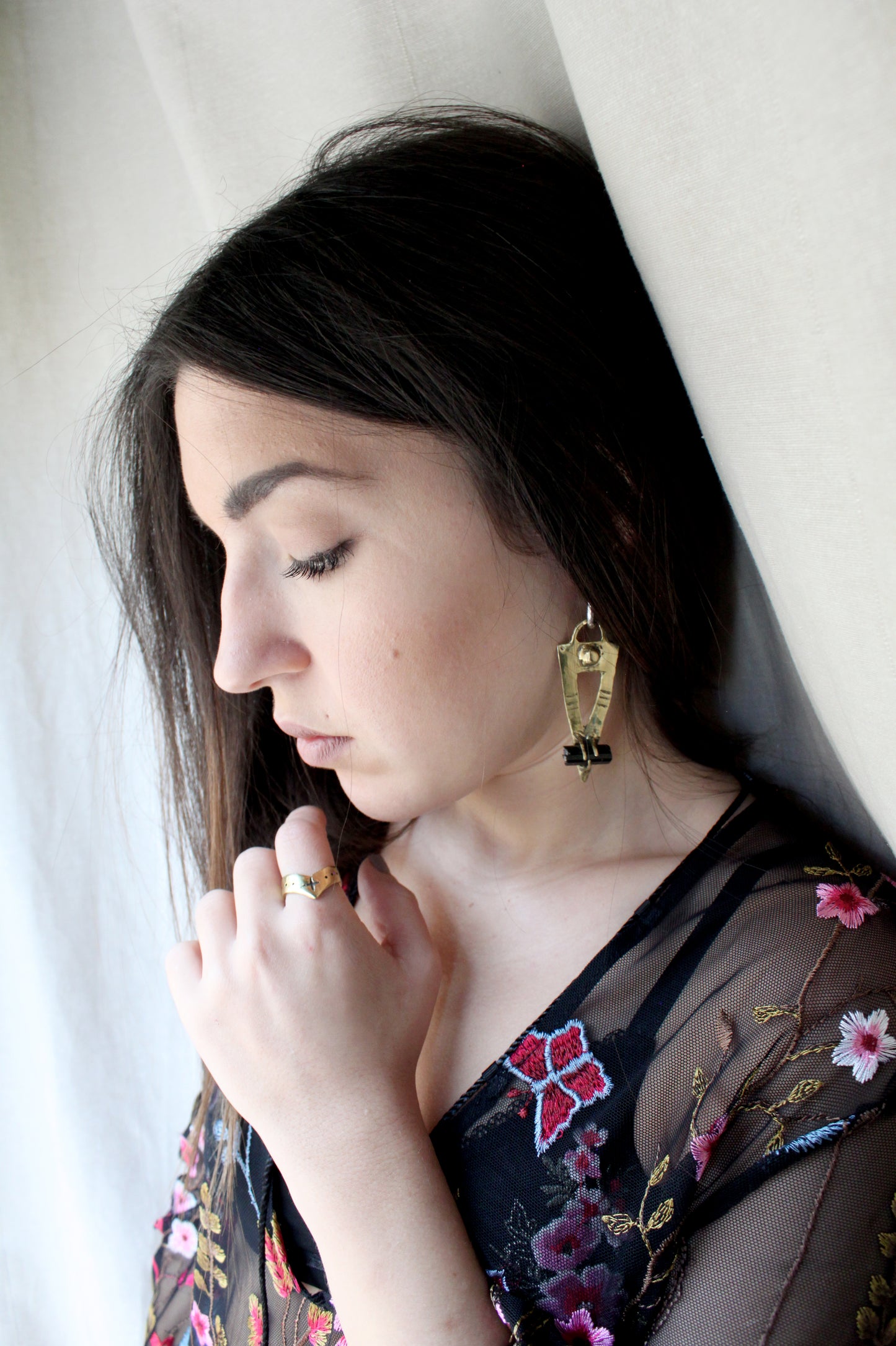 Woman wearing a floral embroidered garment with black tourmaline earrings 