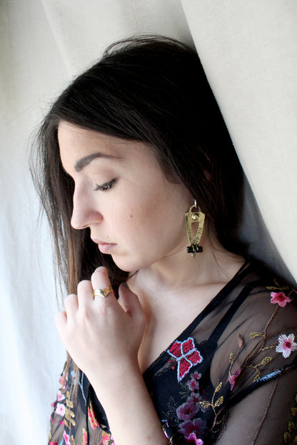 Woman wearing a floral embroidered garment with black tourmaline earrings 
