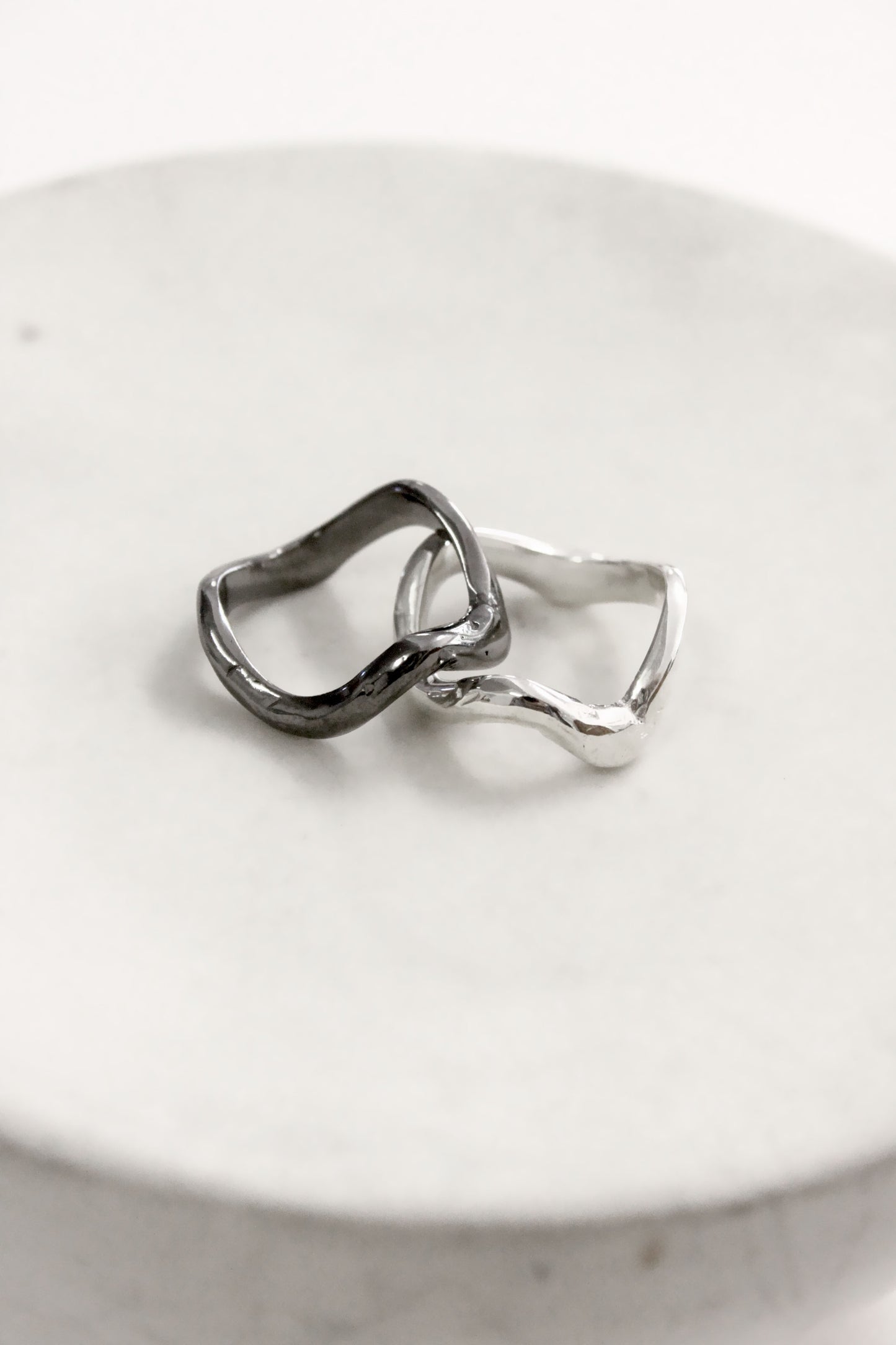 Two silver rings on a white ceramic dish