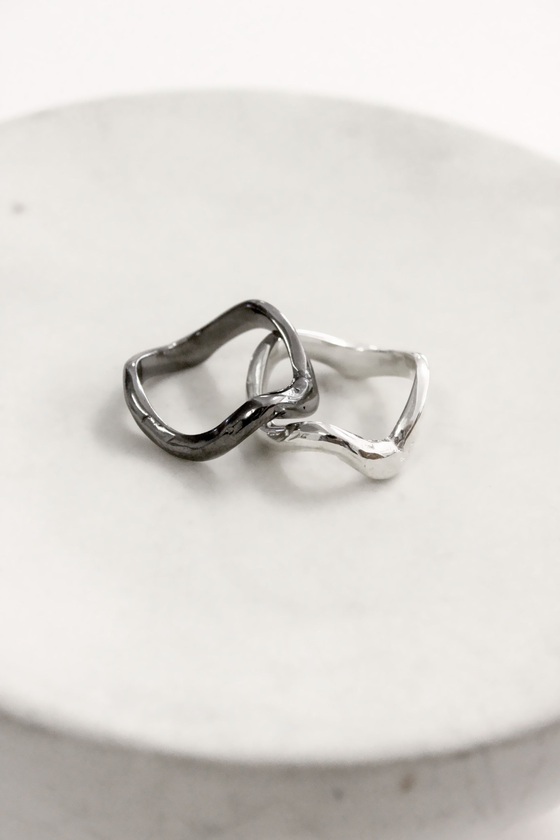 Two silver rings on a white ceramic dish