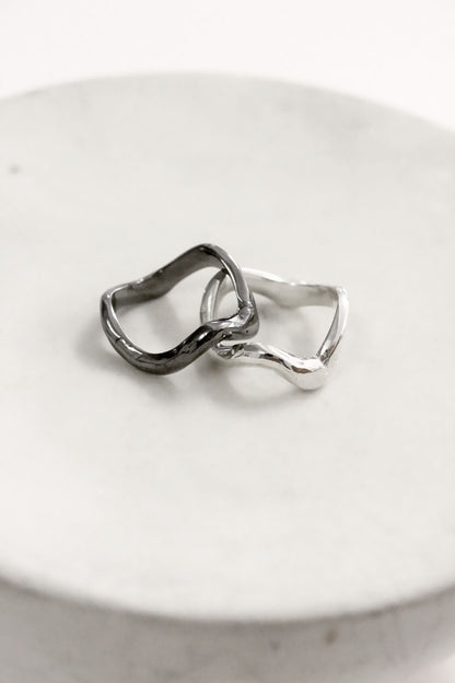 Two silver rings on a white ceramic dish