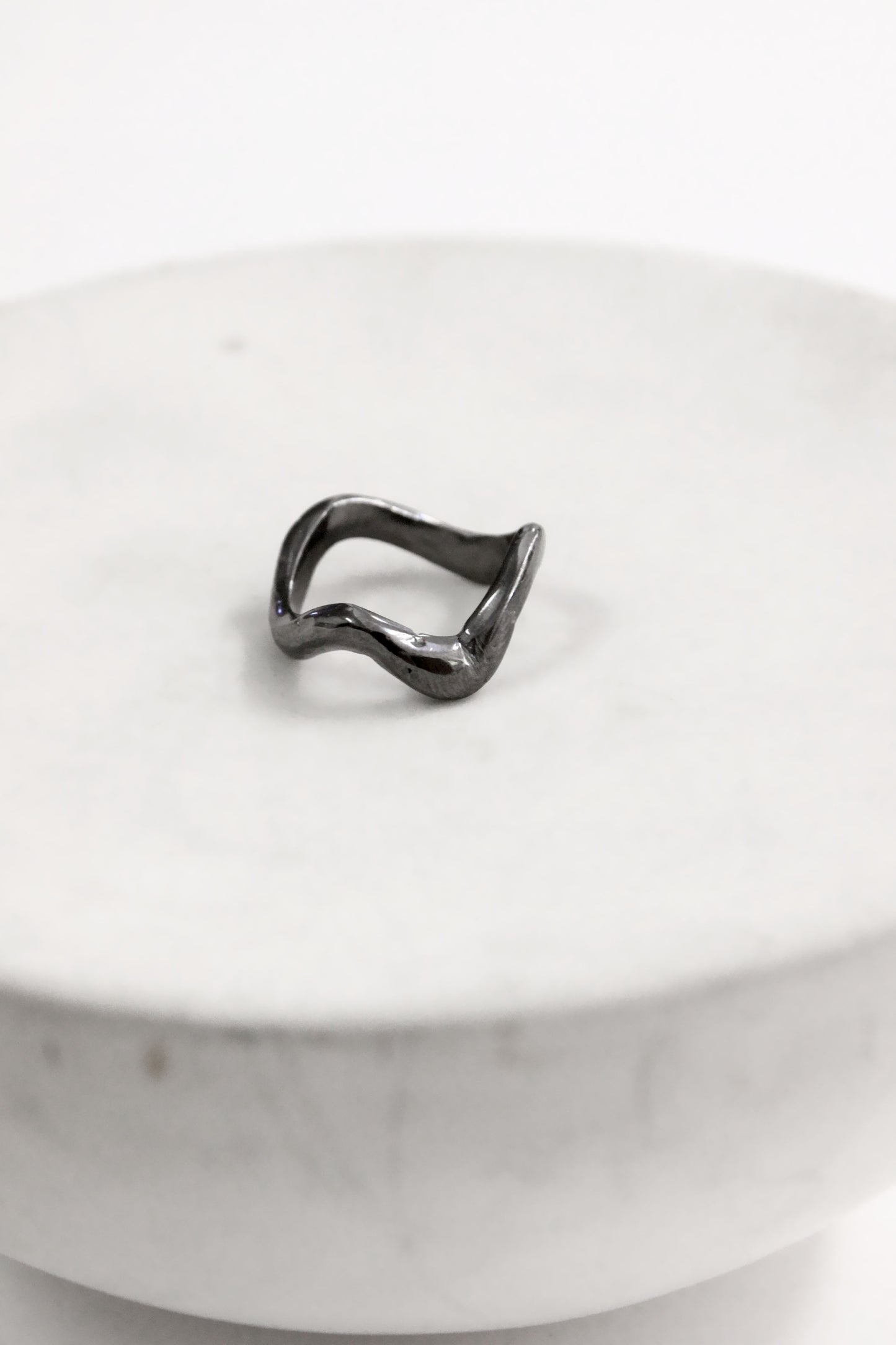 Black abstract ring on a white marble surface