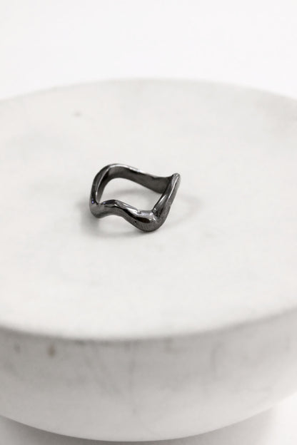 Black abstract ring on a white marble surface