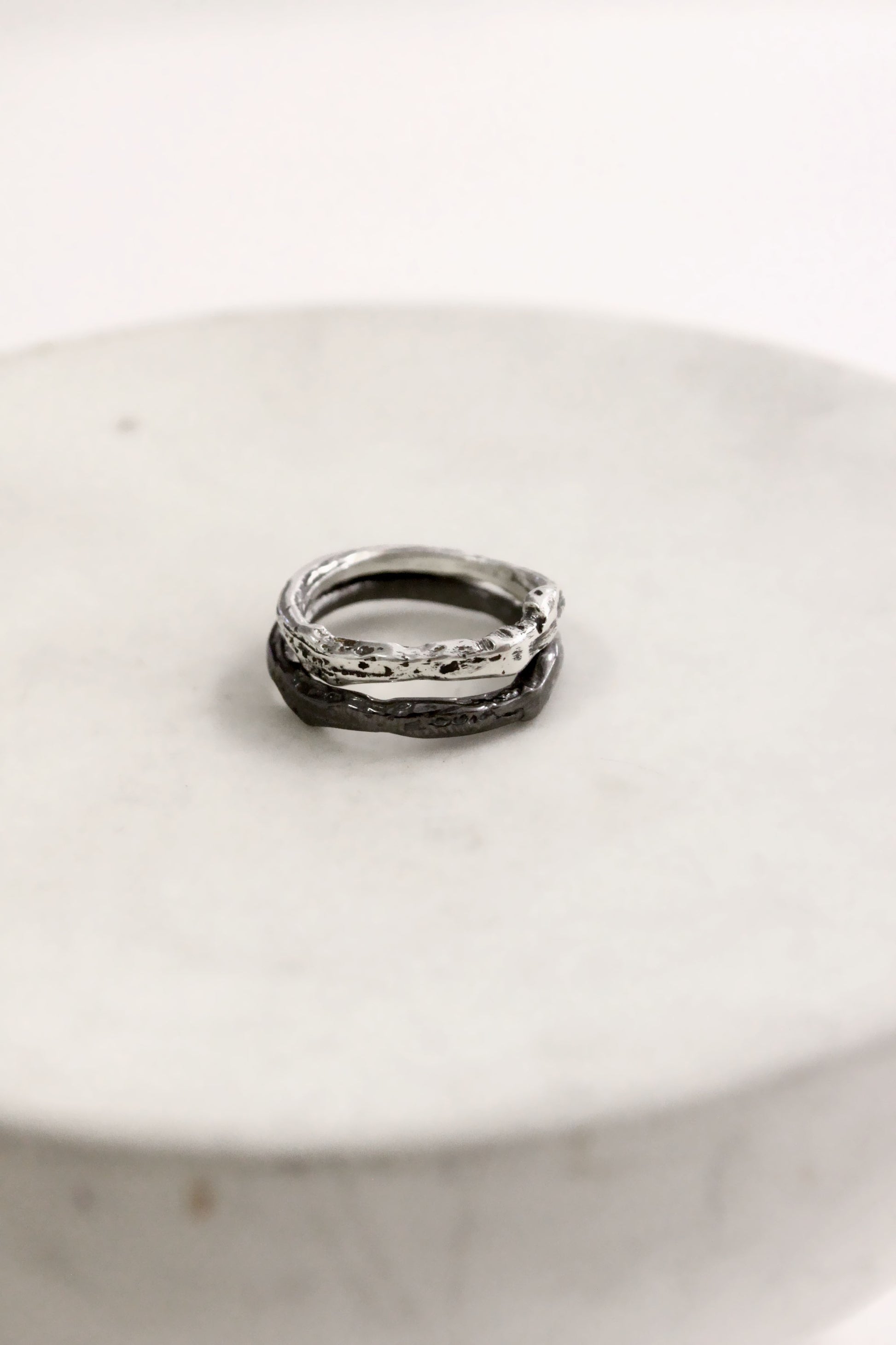 Two silver rings on a white ceramic plate