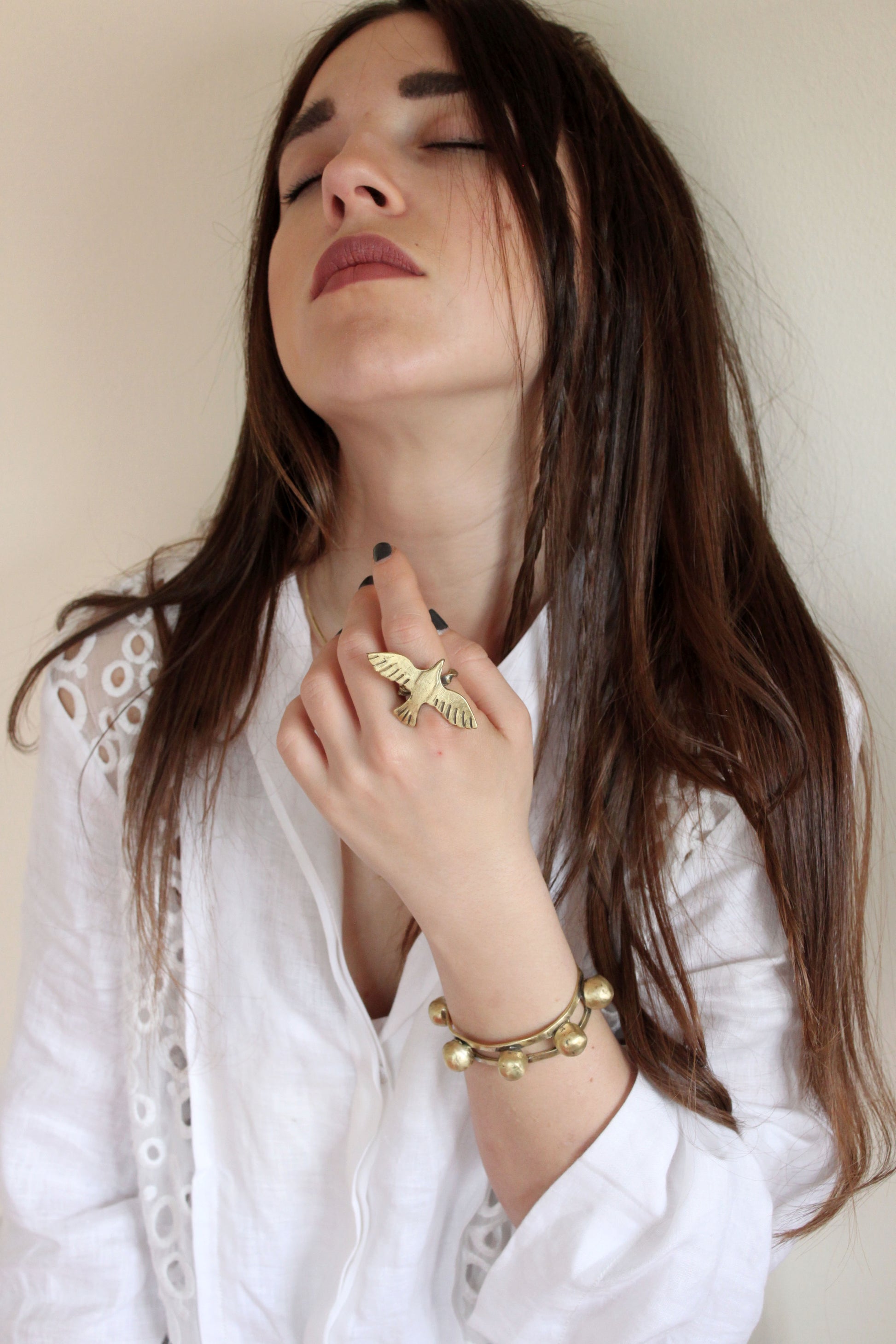 Woman wearing gold jewelry including a bird ring and bracelet 