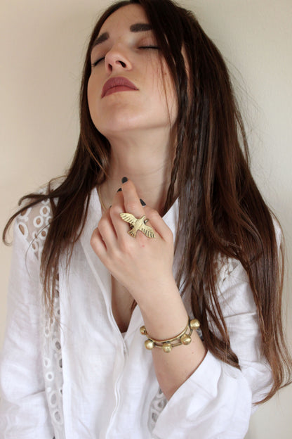 Woman wearing gold jewelry including a bird ring and bracelet 