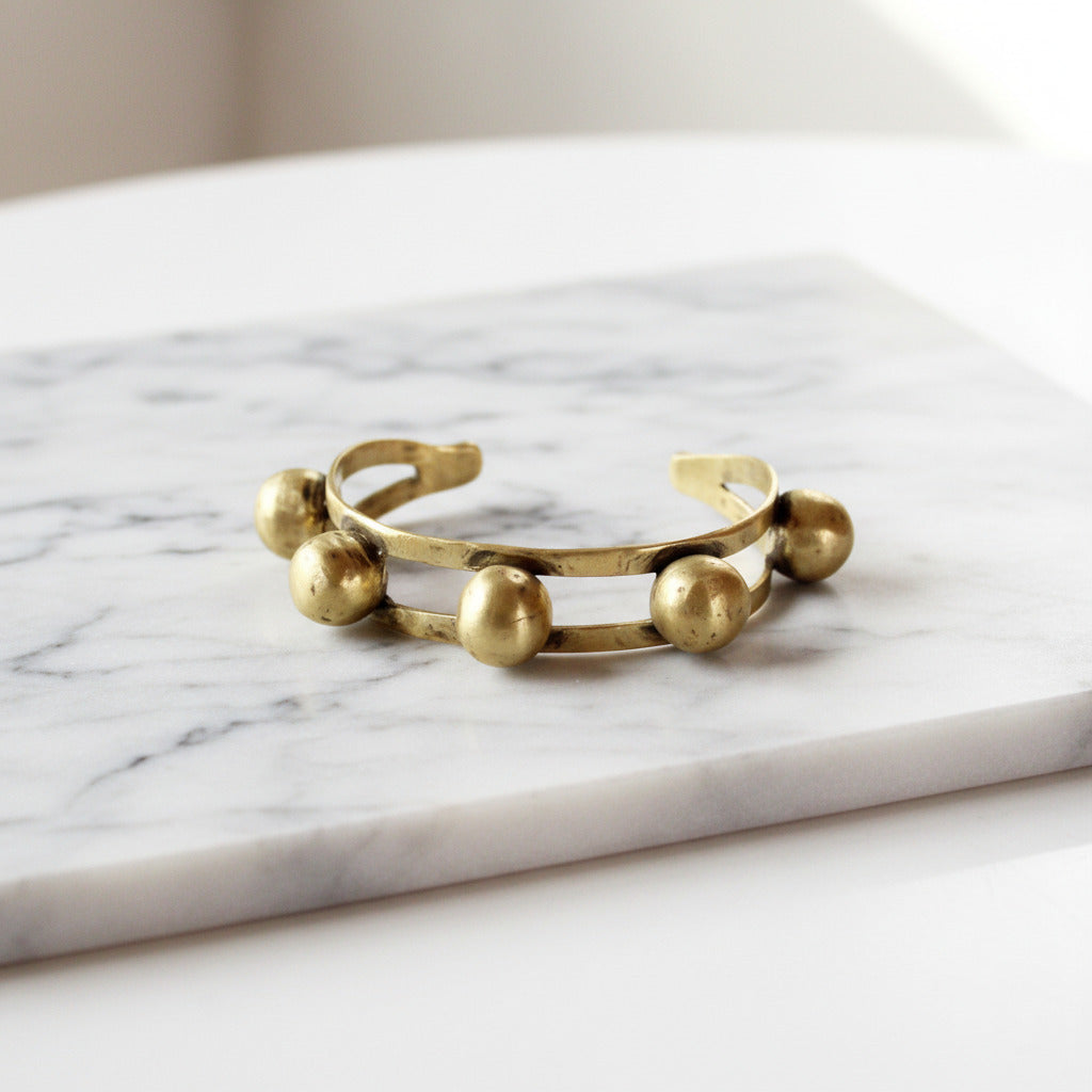 Gold bracelet with spherical beads on a white background