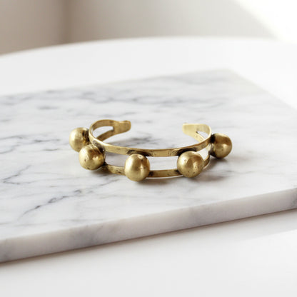 Gold bracelet with spherical beads on a white background