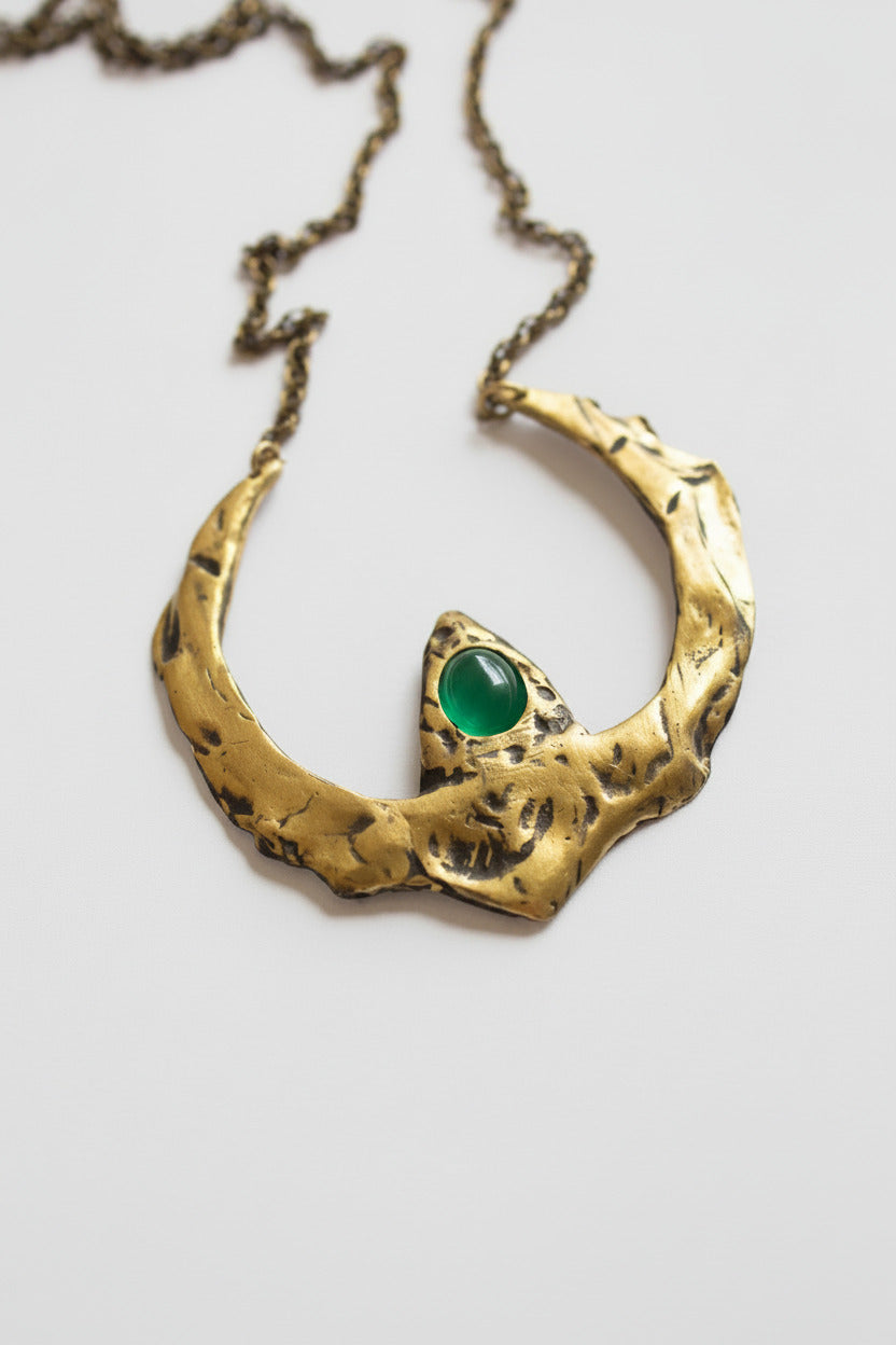 Gold necklace with a green gemstone on a white background