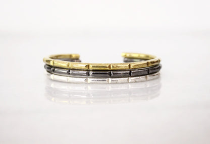 Three-layered bracelet with gold, silver, and black minimal bar cuffs