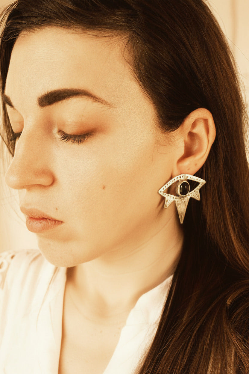 Woman wearing a silver earring with a black gemstone