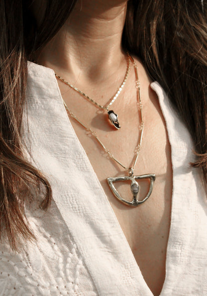  layered necklaces with a focus on a unique pendant.
