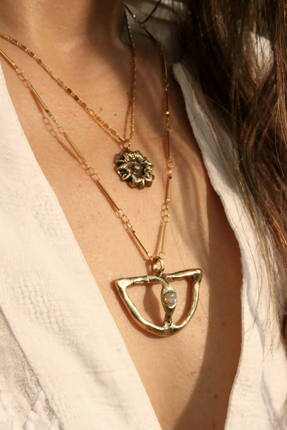  two gold necklaces with floral and geometric pendants.