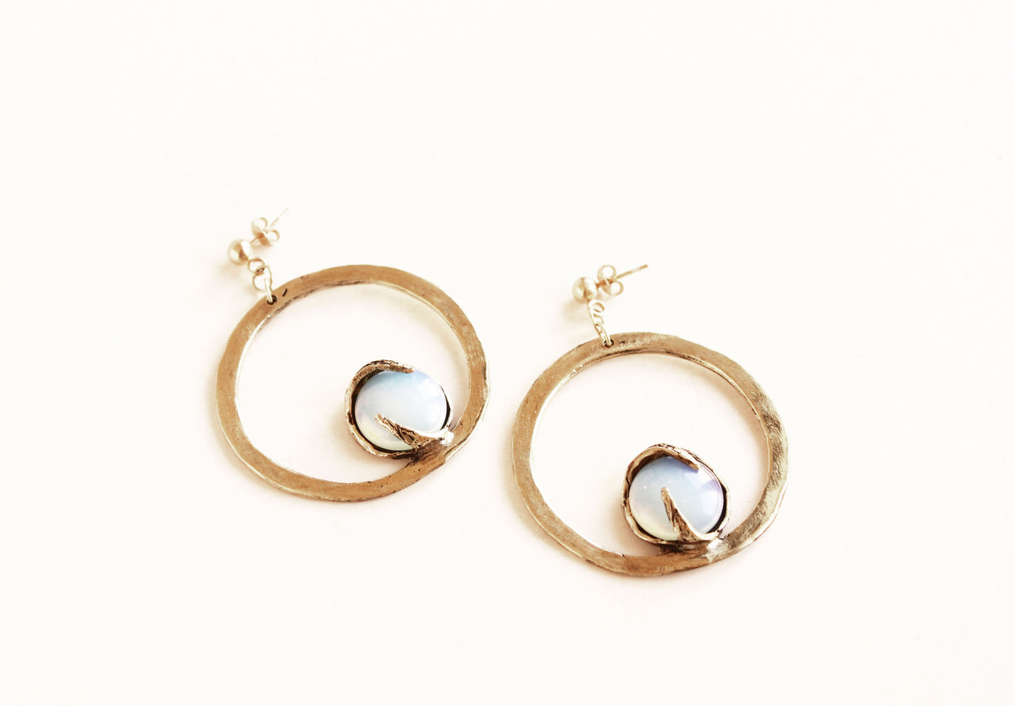 Gold hoop earrings with a central gemstone on a white background