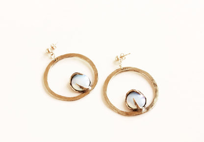 Gold hoop earrings with a central gemstone on a white background