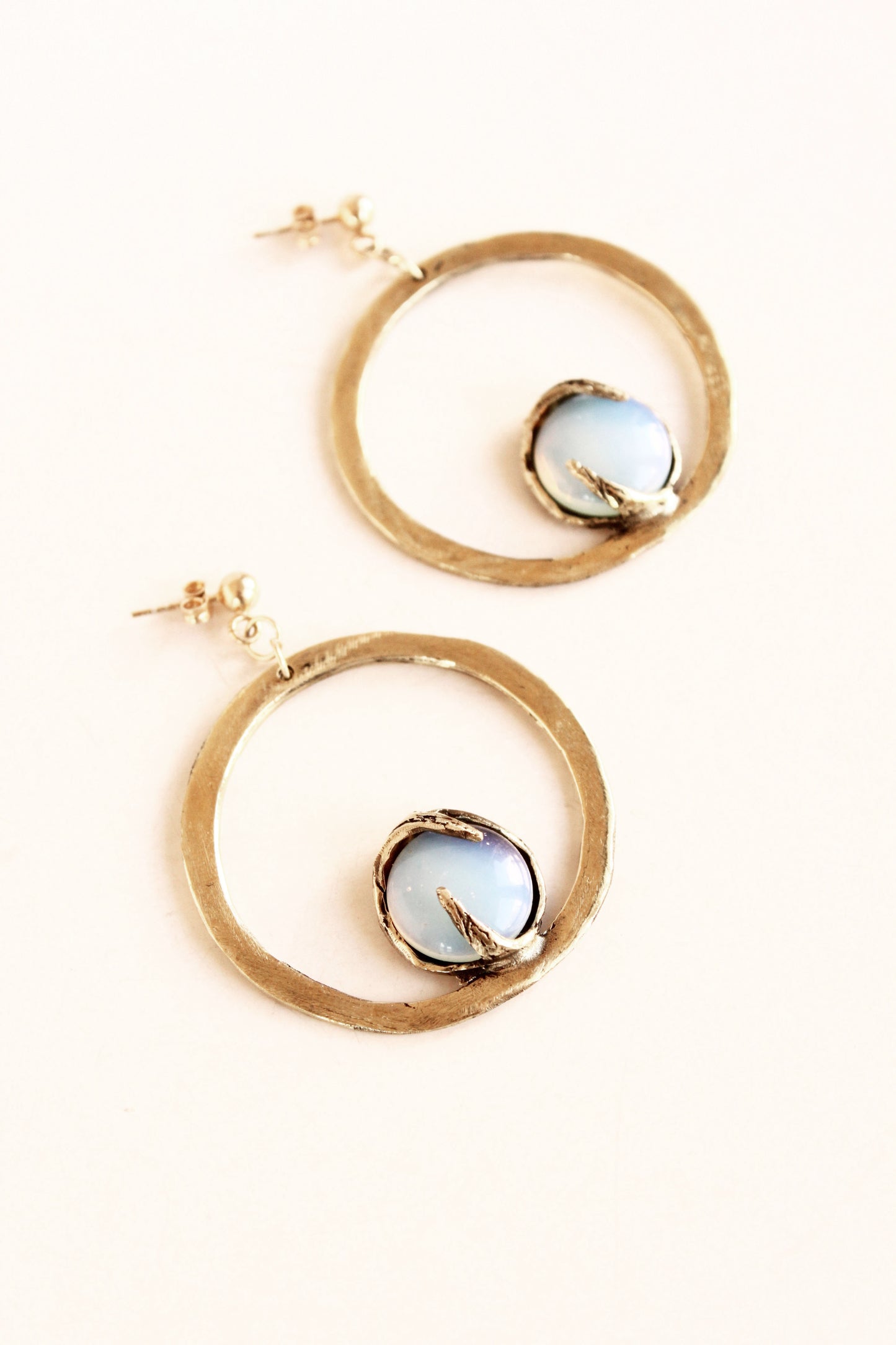 Gold hoop earrings with circular gemstones on a white background