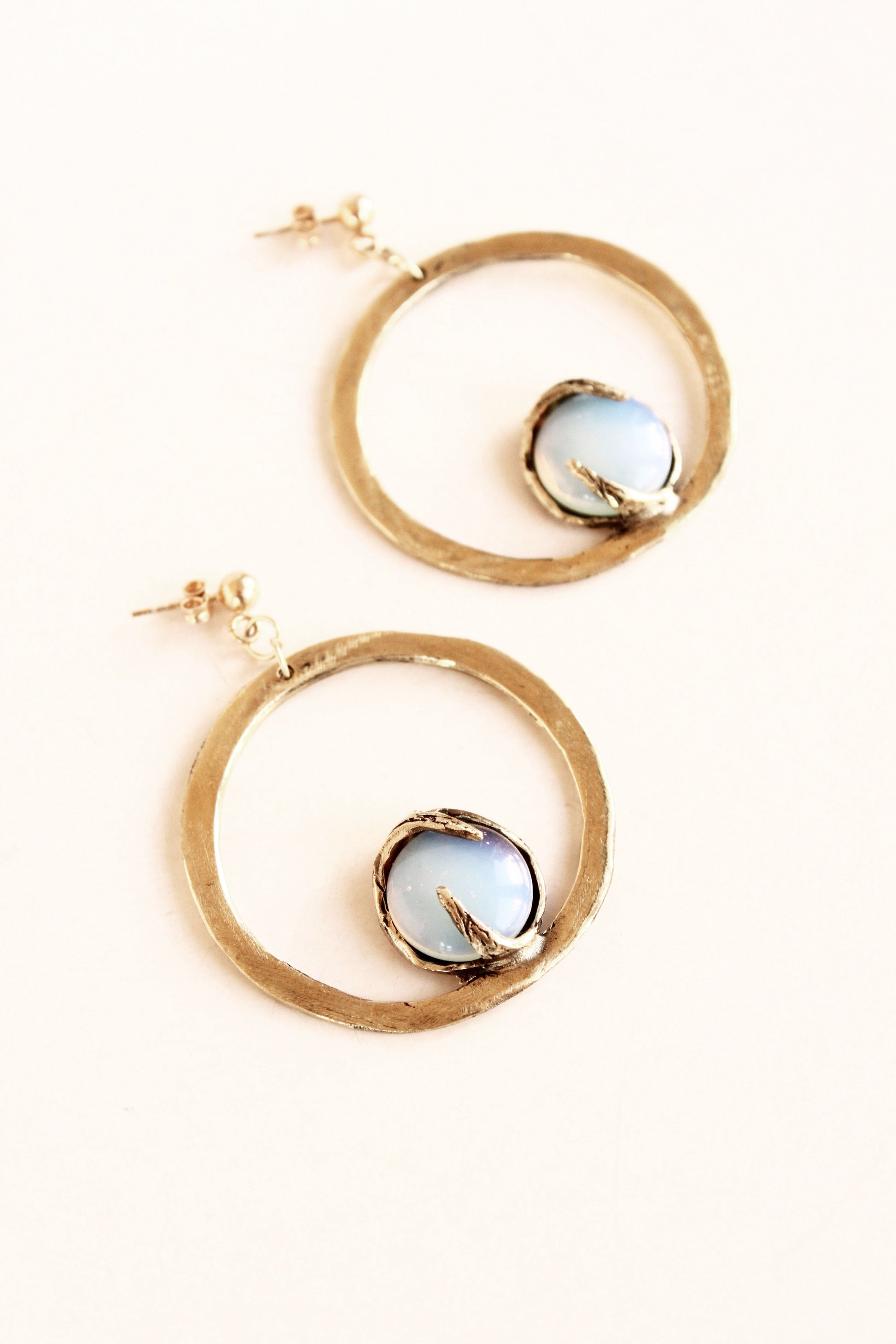 Gold hoop earrings with circular gemstones on a white background