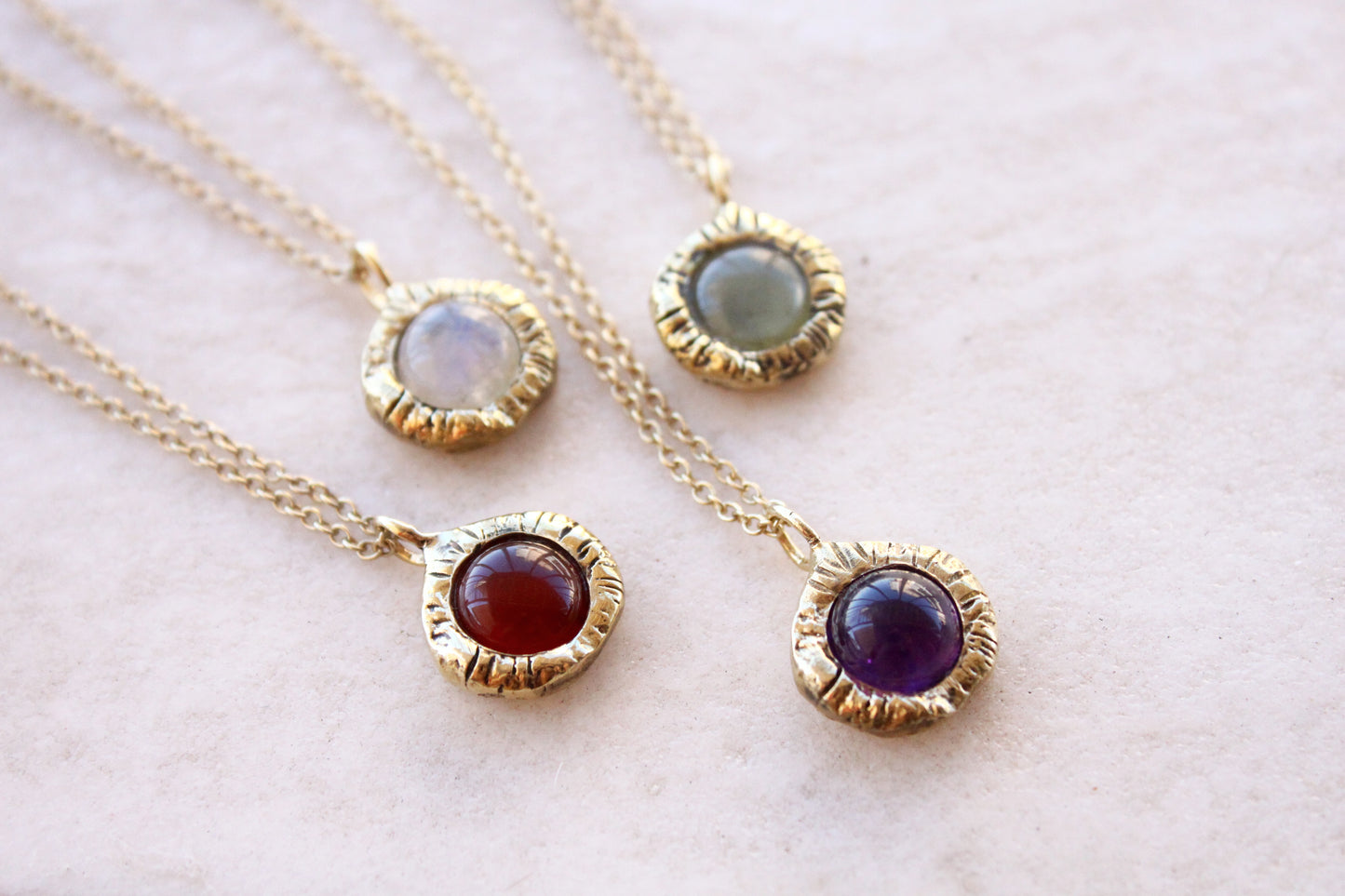 Three gold necklaces with gemstone pendants. 