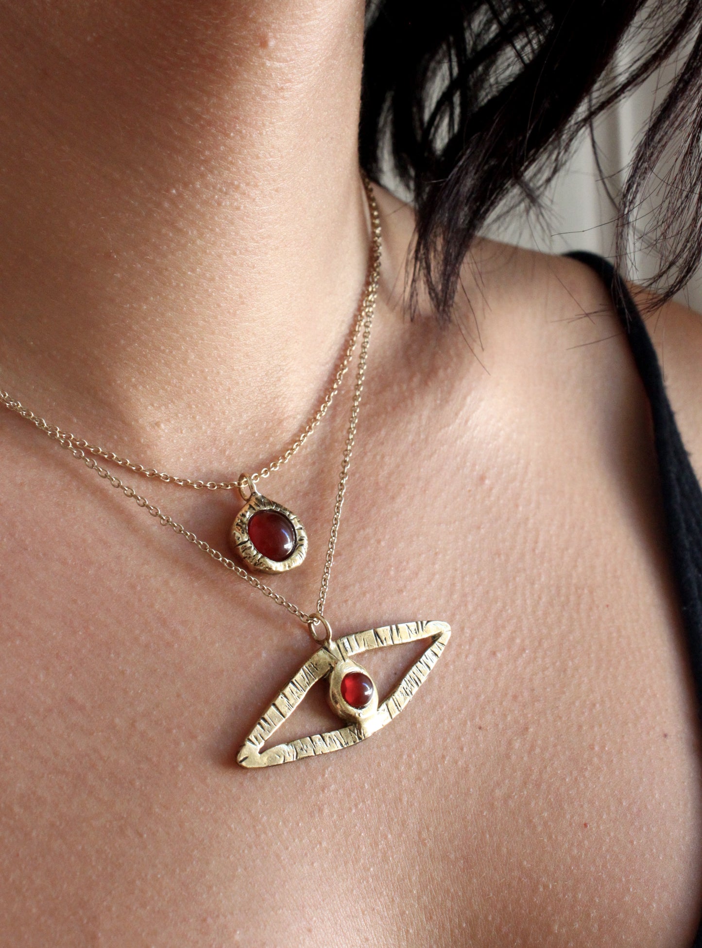 Gold necklaces with eye-shaped pendants on a person's neck
