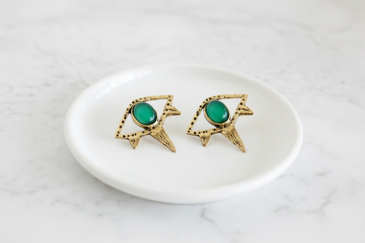 Gold earrings with green gemstones on a white background