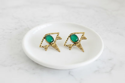 Gold earrings with green gemstones on a white background