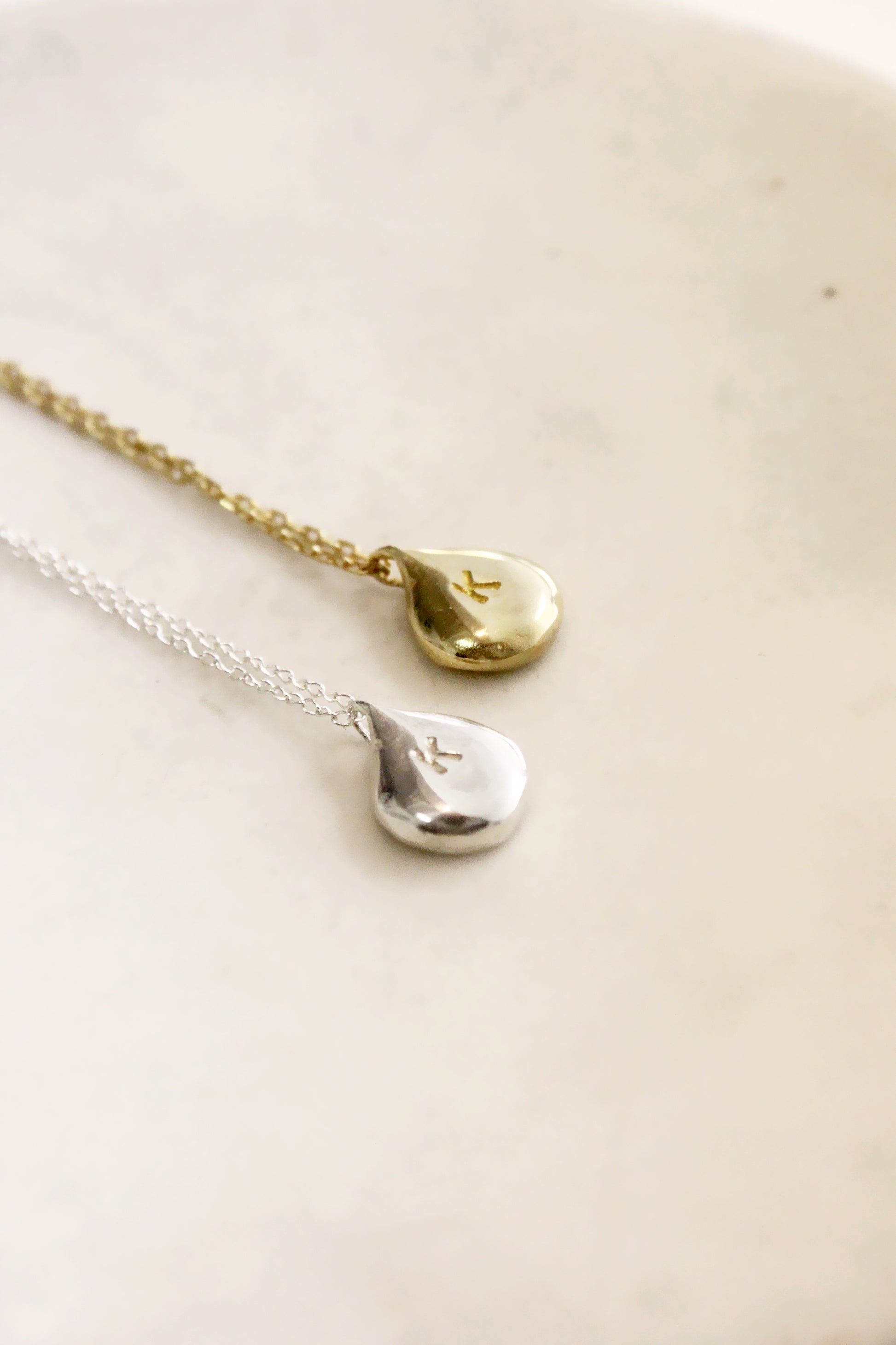 Two gold and silver teardrop-shaped personalized monogram pendants