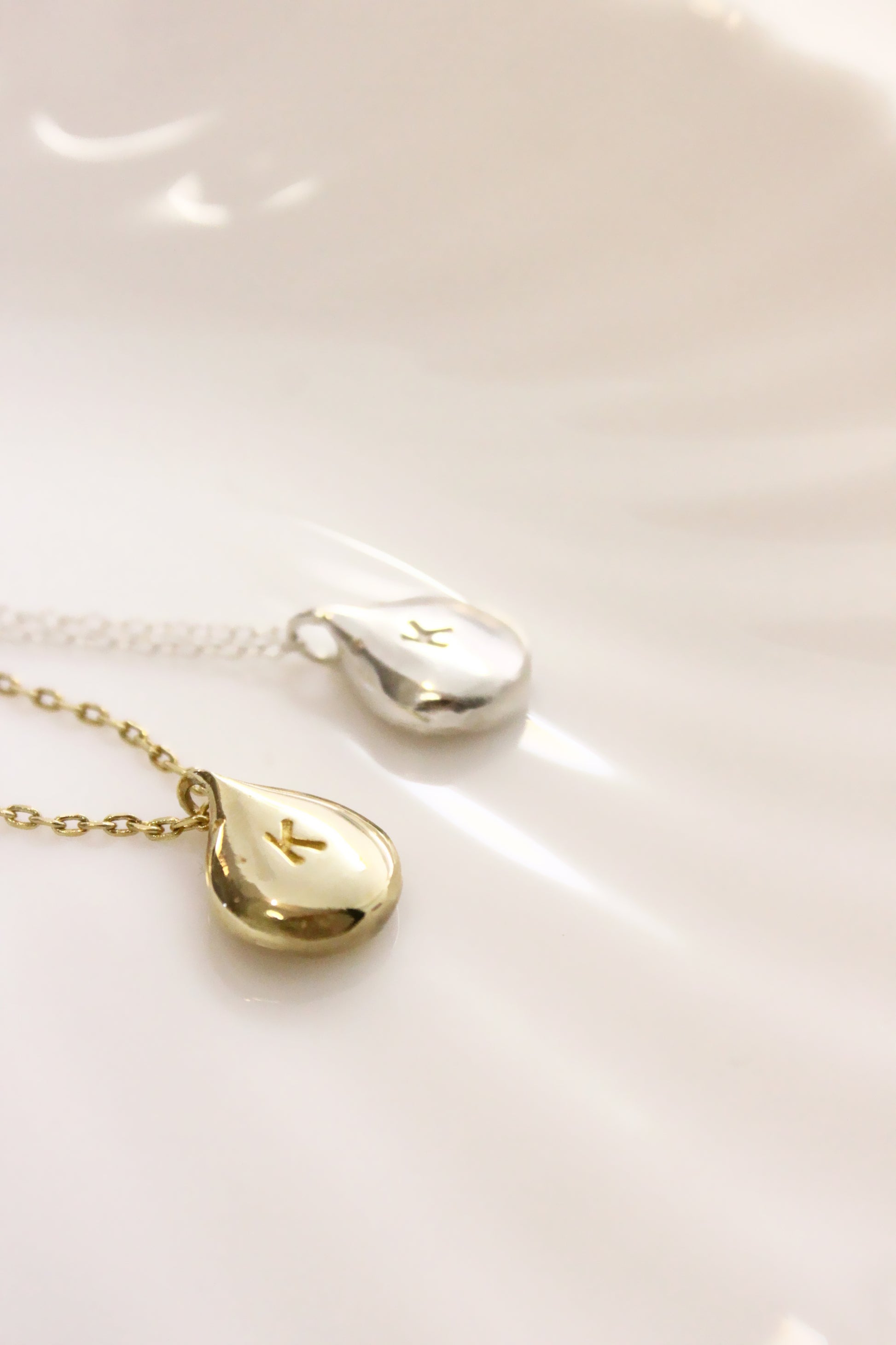Gold and silver teardrop-shaped pendants on a white dish