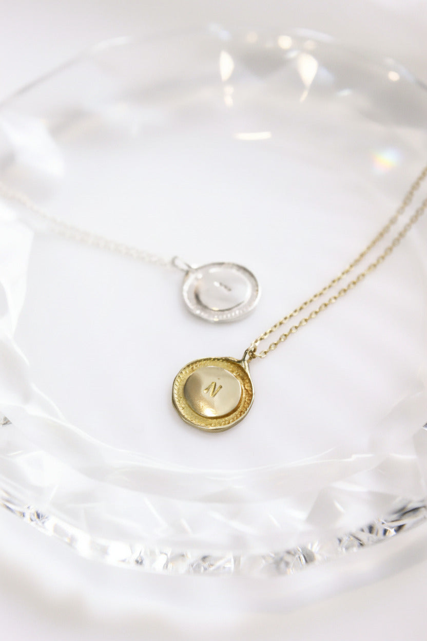 Gold necklace with a round pendant on a white background