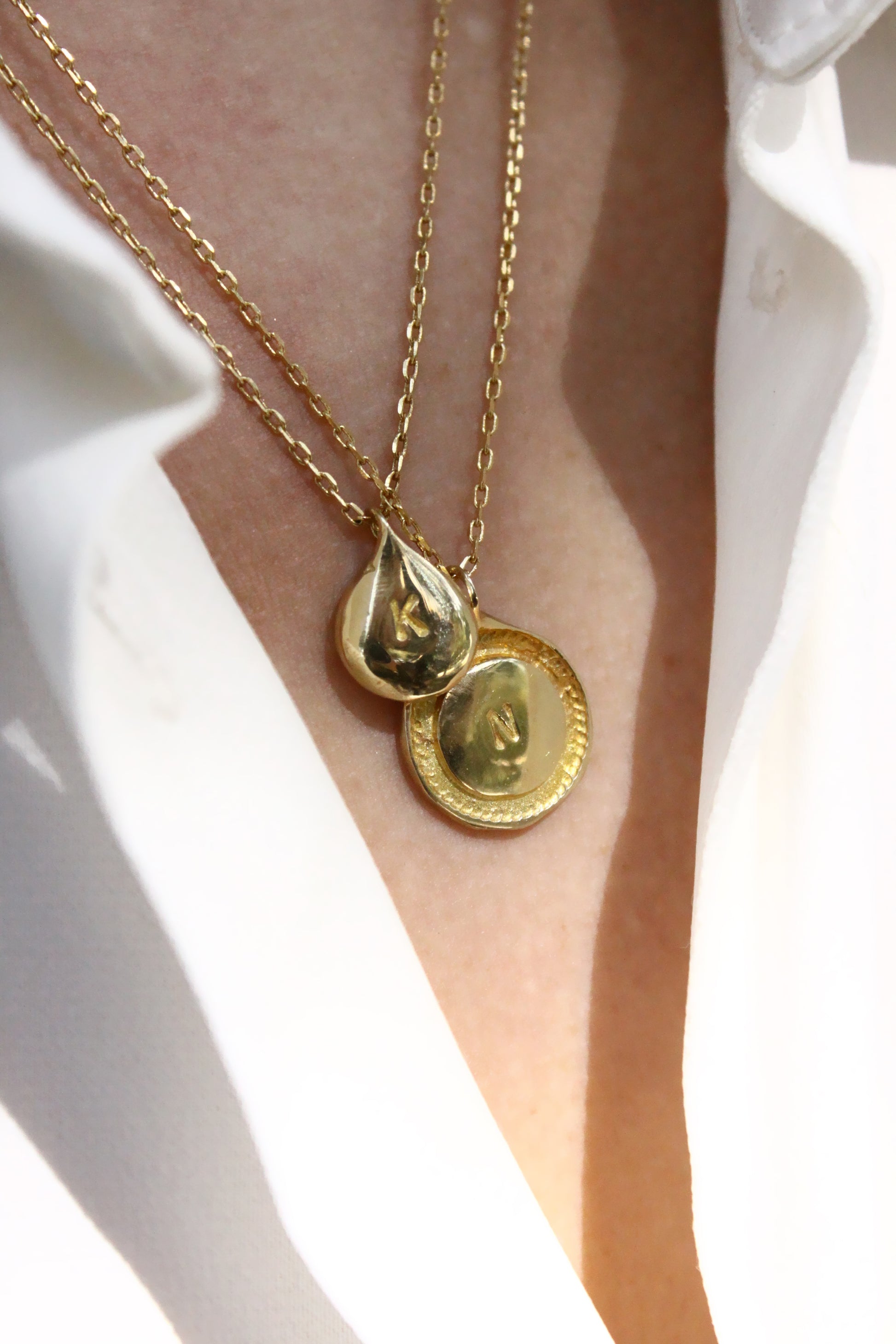 Gold necklaces with circular monogram pendants 