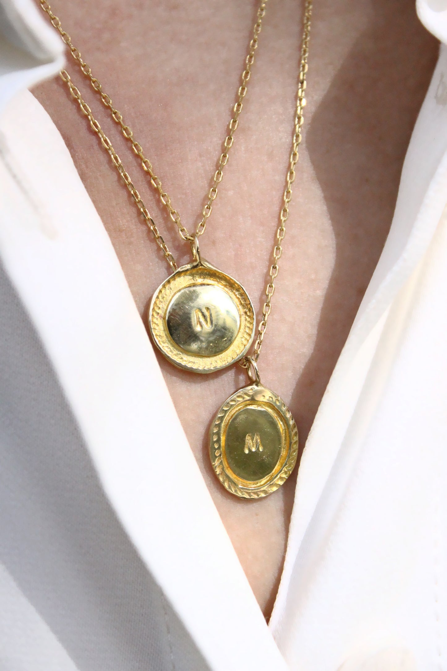 Gold necklaces with circular pendants on a white background
