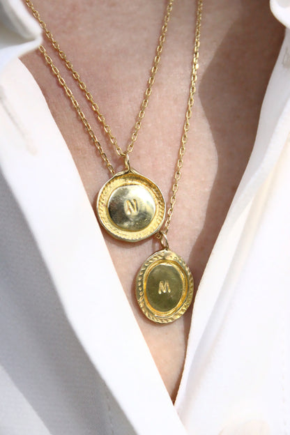 Gold necklaces with circular pendants on a white background