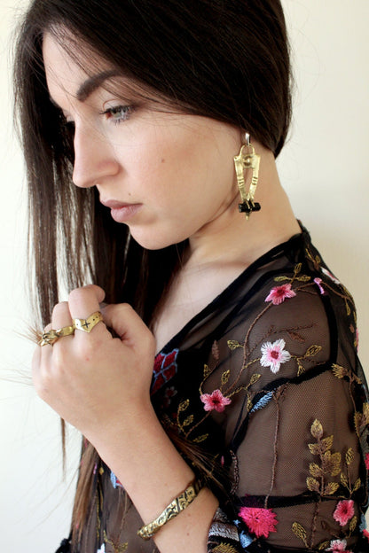 Woman wearing a floral embroidered blouse with black tourmaline earrings hoops