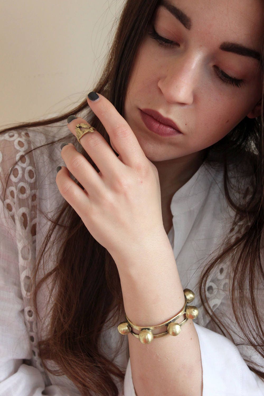 Woman wearing a gold bracelet with a neutral background