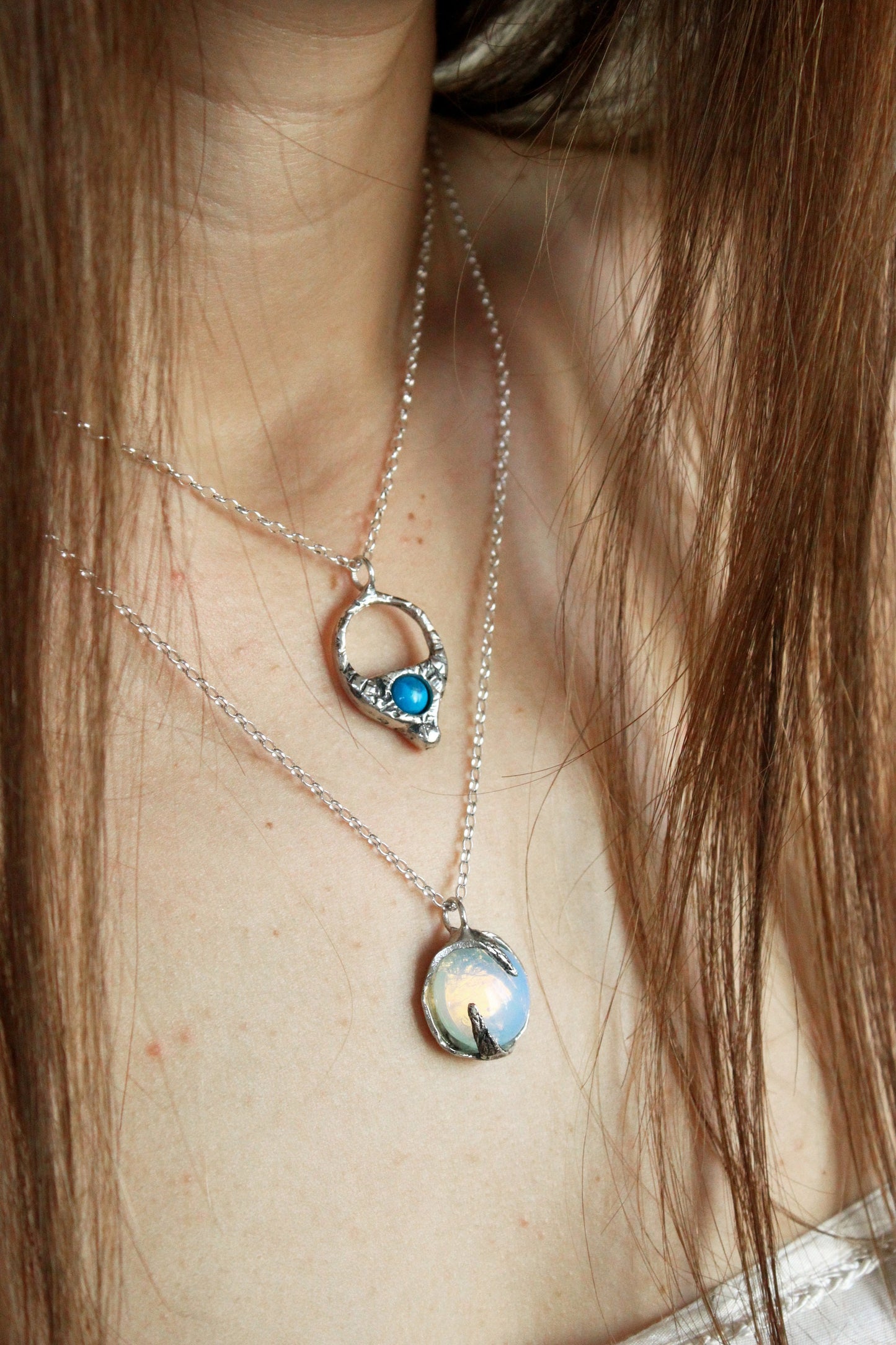 two silver necklaces with opal and turquoise crystals.
