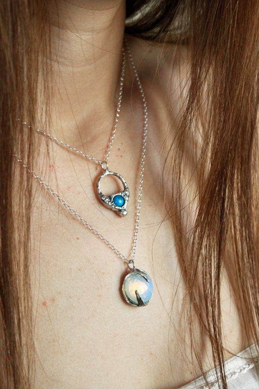 two silver necklaces with opal and turquoise crystals.