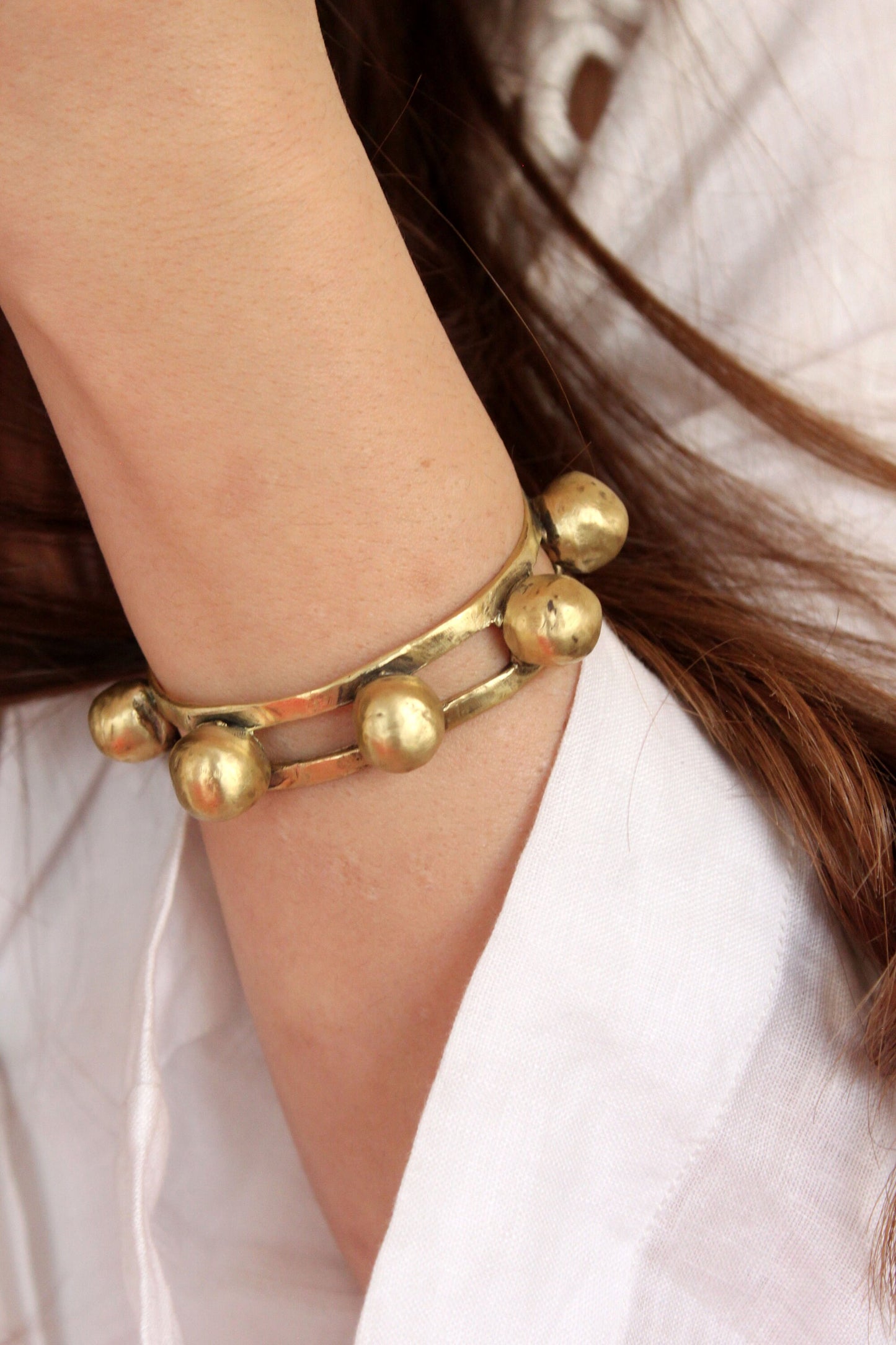 Gold bracelet on a wrist with a neutral background