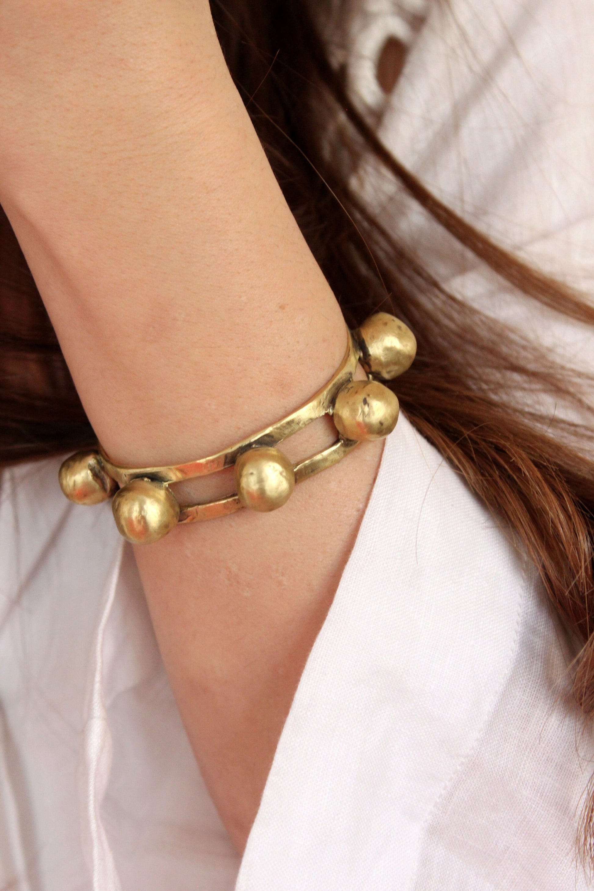 Gold bracelet on a wrist with a neutral background