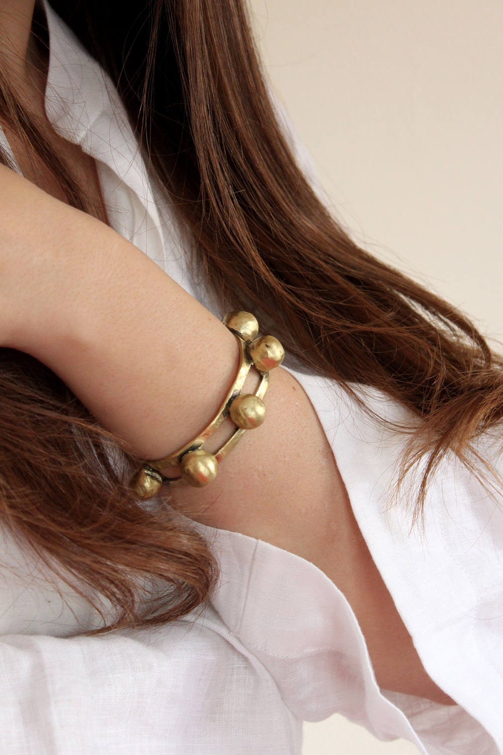 Gold bracelet on a wrist with a neutral background