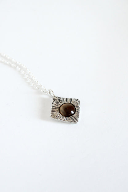 Necklace with a rhombus pendant featuring a brown stone on a white background