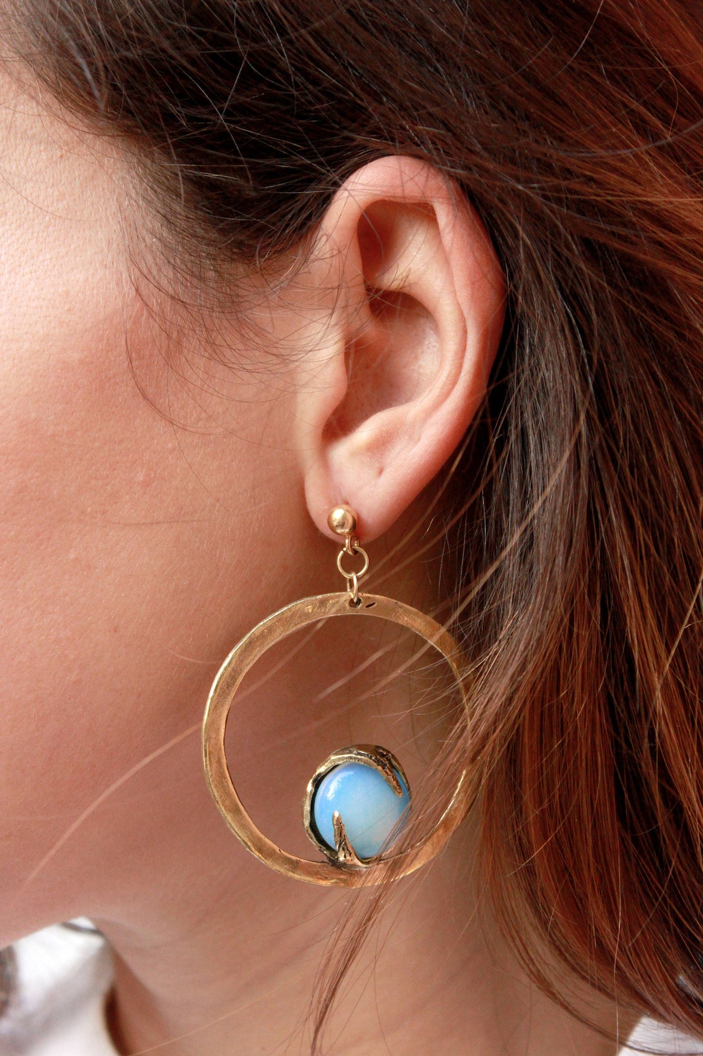  a gold hoop earring with a opal gemstone.