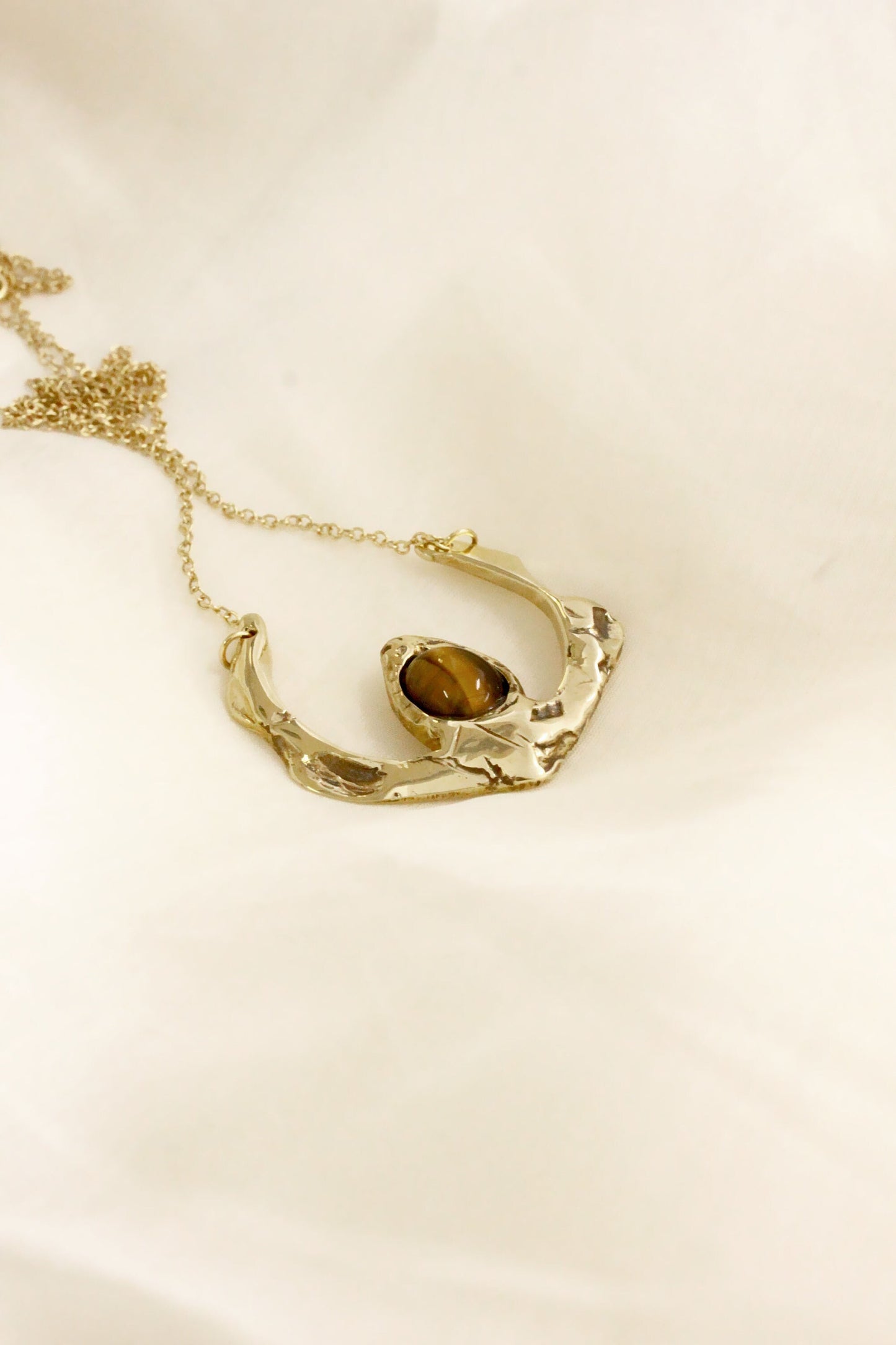 Gold necklace with a central gemstone on a beige background