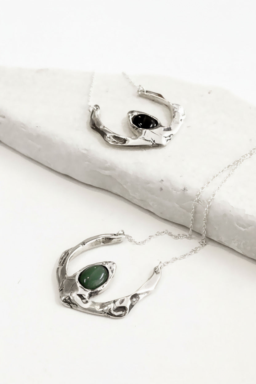 Silver jewelry with green stones on a white surface