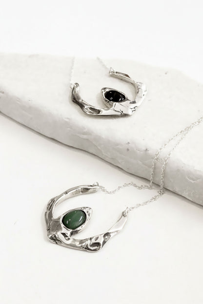 Silver jewelry with green stones on a white surface