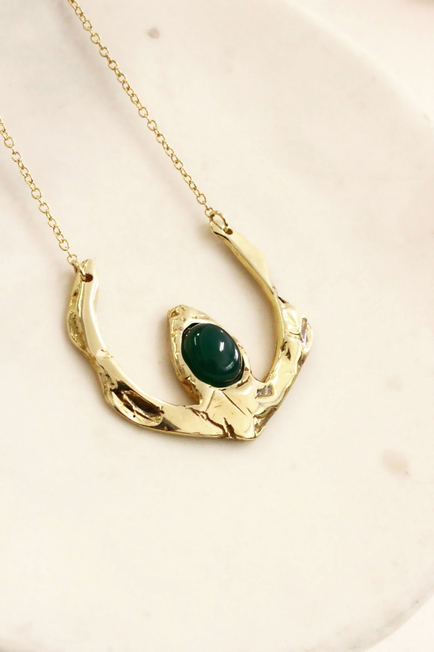 Gold necklace with a green gemstone 