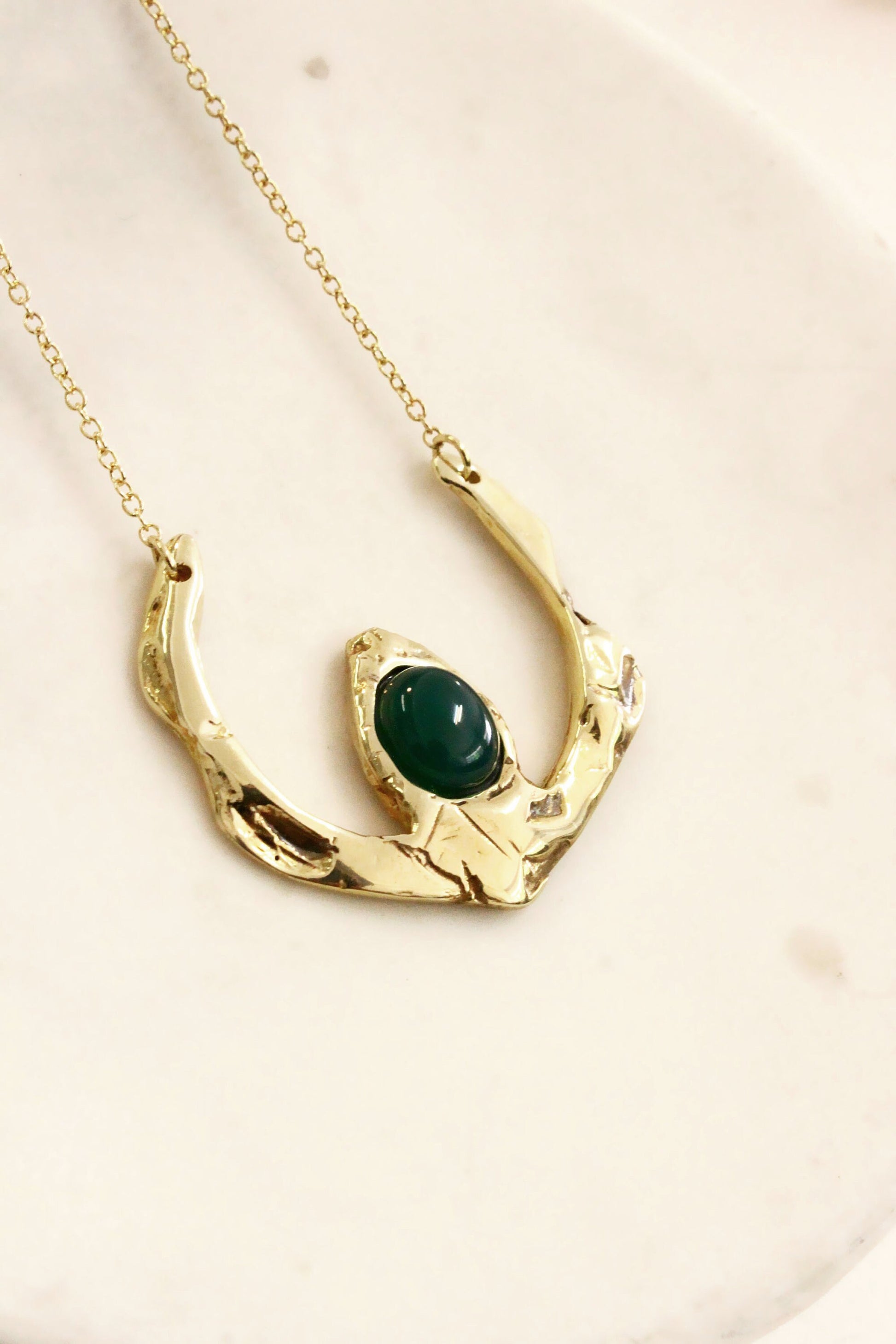Gold necklace with a green gemstone 