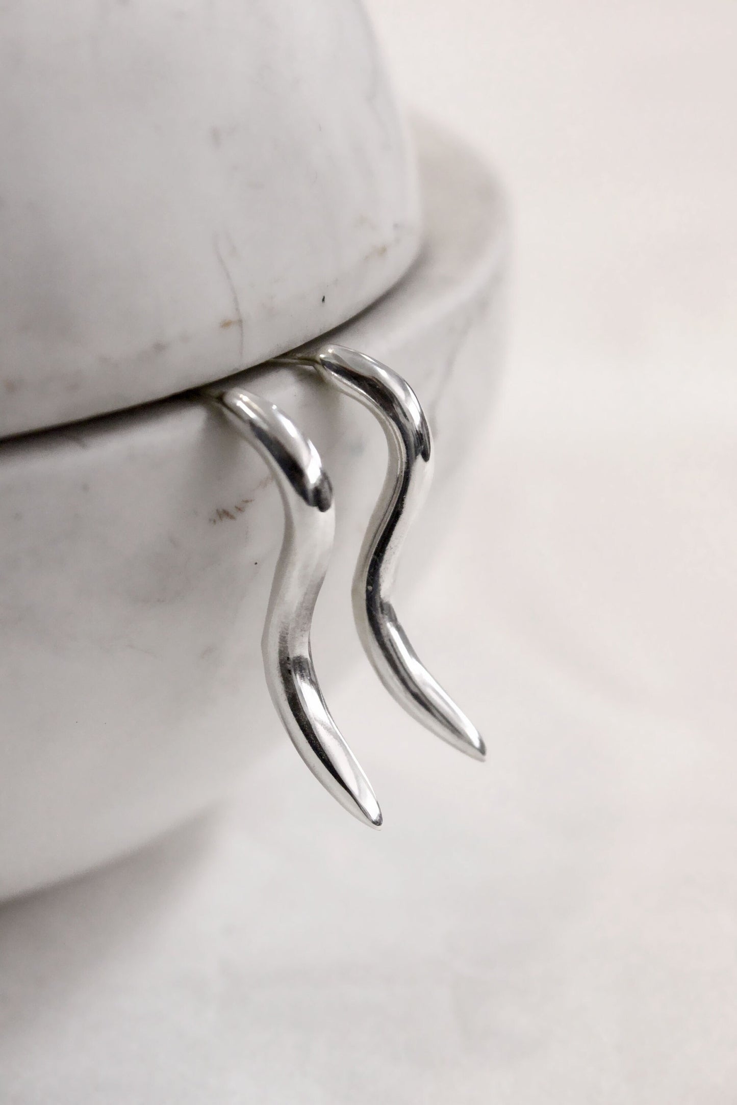 Silver pair of earrings on a marble surface