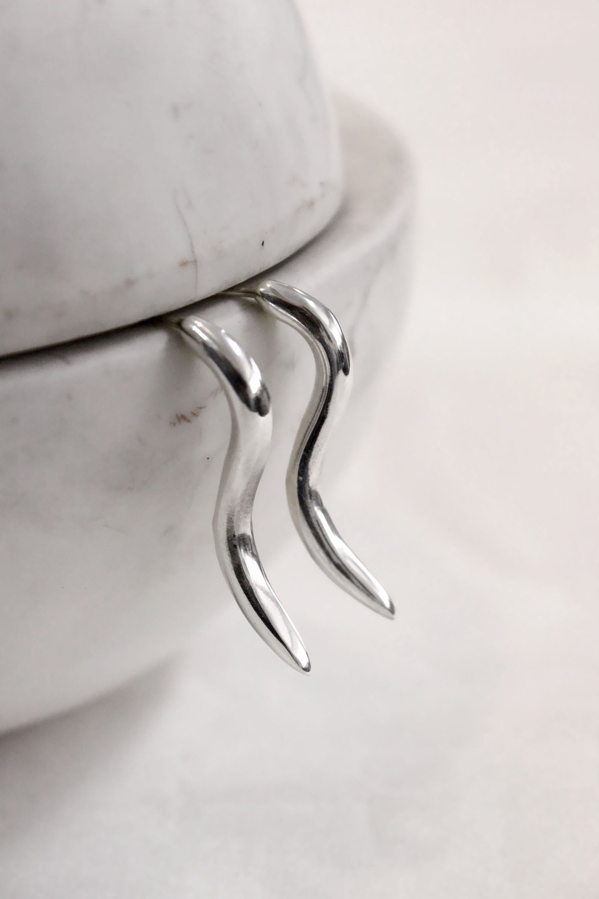 Silver pair of earrings on a marble surface